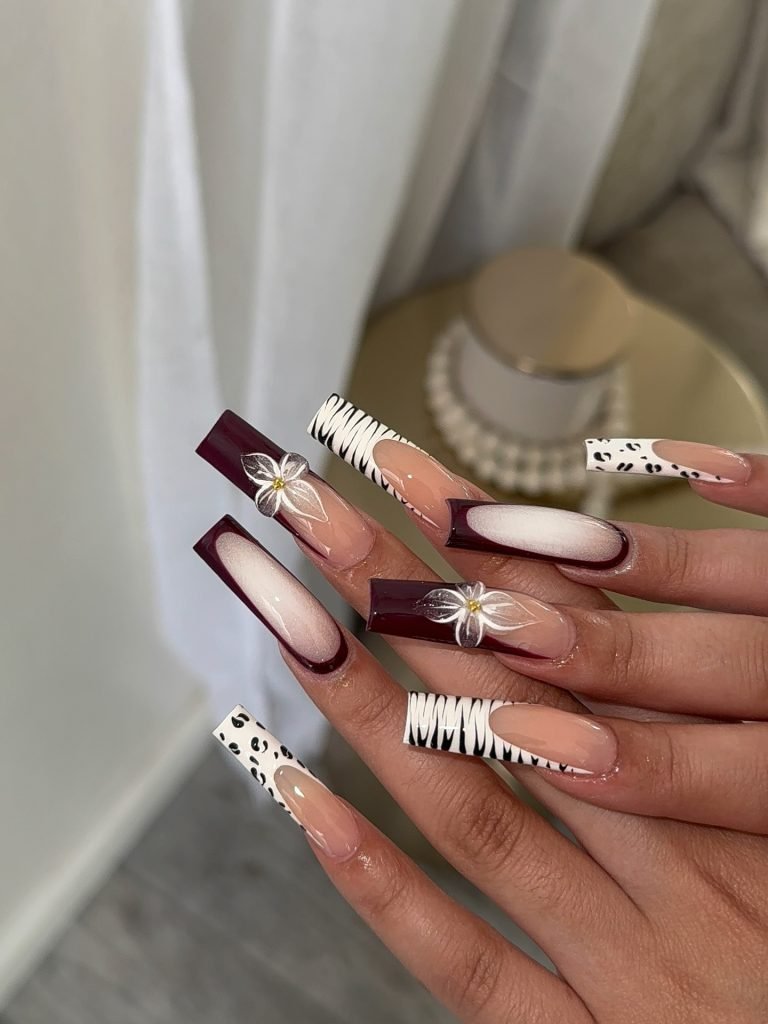 Elegant manicure with burgundy, animal print, and floral designs on long coffin-shaped nails.