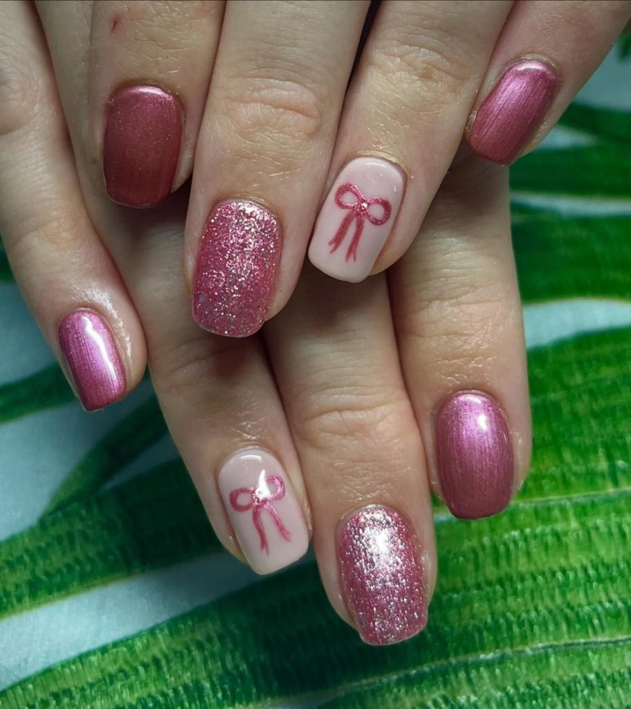 Pink and glitter nail art with ribbon design on accent nails, showcasing a trendy manicure style.