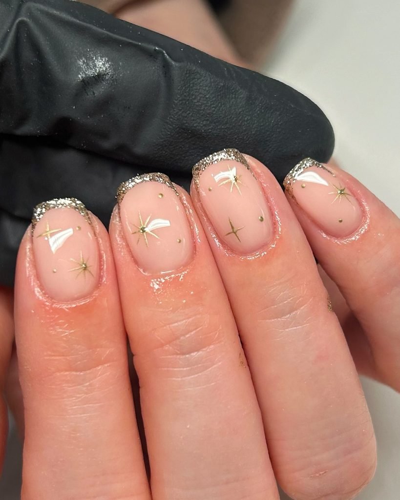 Glittery star-themed nail art with gold accents on a natural base, showcasing elegant nail design.