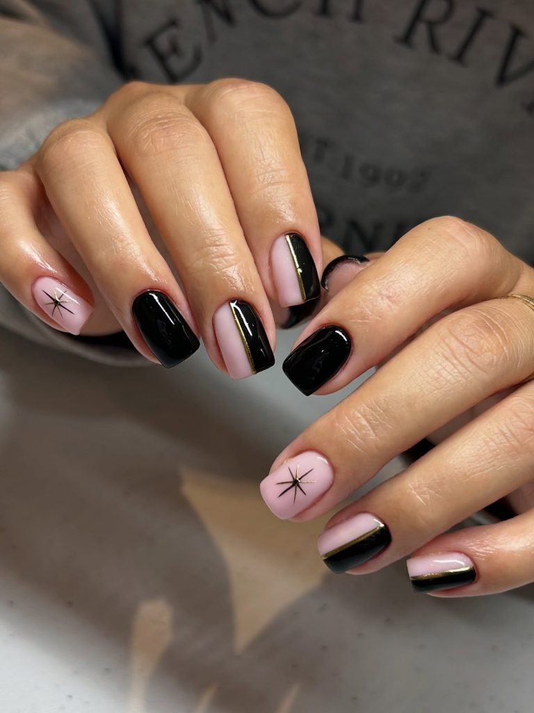 Chic black and pink manicure with gold accents and star design on short nails. Modern and stylish nail art.