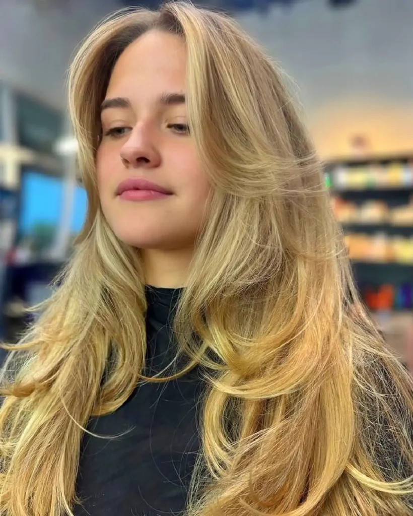 Woman with long, blonde hair in a salon setting, showcasing smooth and voluminous locks.